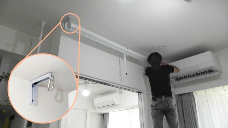 カラビナを使ってプロジェクタースクリーンを取り付ける様子