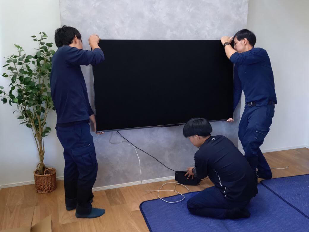 テレビ本体を壁掛け金具へ取り付けている様子
